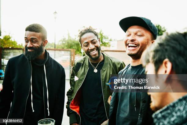 laughing friends in discussion while hanging out at outdoor bar - african american photos et images de collection