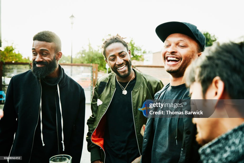 Laughing friends in discussion while hanging out at outdoor bar