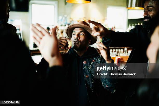 smiling friends having an animated conversation in bar - black men hanging out stock pictures, royalty-free photos & images