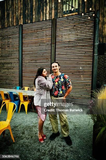 portrait of couple standing in courtyard of outdoor restaurant - multi coloured trousers stockfoto's en -beelden