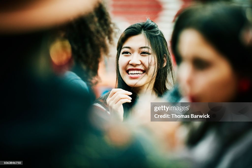 Smiling woman hanging out with friends during party at outdoor bar