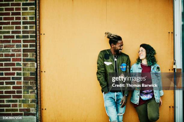 portrait of smiling friends standing in front of yellow wall - flirting stock-fotos und bilder