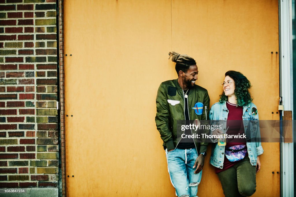 Portrait of smiling friends standing in front of yellow wall