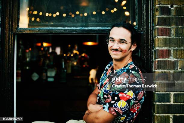 smiling man sitting in window with lipstick kiss on cheek - handsome native american men stock-fotos und bilder