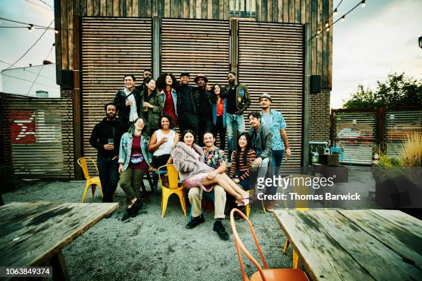 friends posing for group photo during party at outdoor restaurant - millennial generation stock pictures, royalty-free photos & images