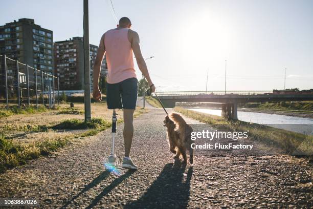 recovering man spending time with his dog by a river - prosthetic limb stock pictures, royalty-free photos & images