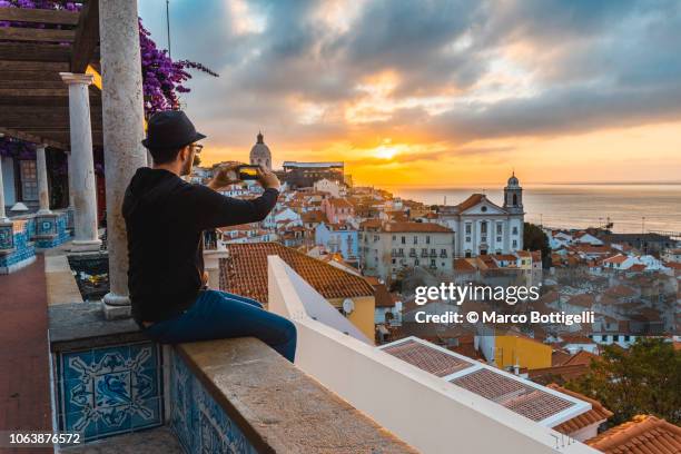 tourist photographing with smartphone at sunrise in lisbon, portugal - portugal stockfoto's en -beelden