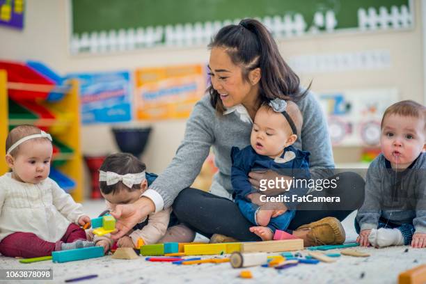 pre school teacher playing with babies - toddler musical instrument stock pictures, royalty-free photos & images
