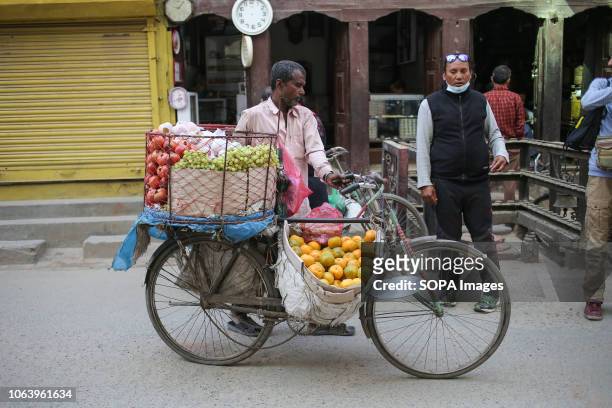 Man seen pushing a bicycle full of fruits. Daily life in Thamel, a commercial and touristic neighborhood in the capital of Nepal, Kathmandu.