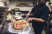 Chef takes out a hot pizza from the oven