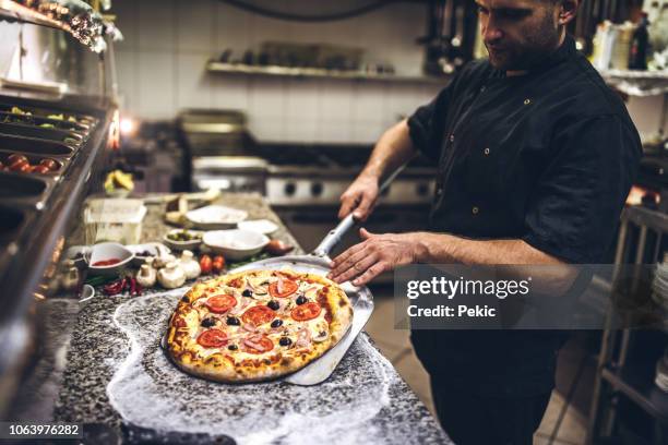 chef takes out a hot pizza from the oven - pizza restaurant stock pictures, royalty-free photos & images