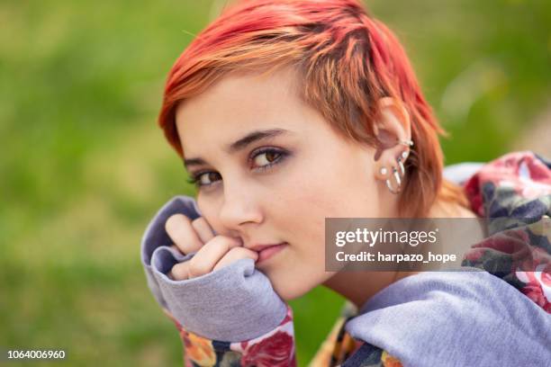 portrait of a girl with red hair and green, grassy background. - earring stud stock pictures, royalty-free photos & images