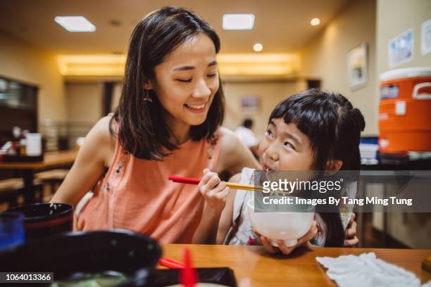 pretty young mom having meal joyfully with her lovely daughter in a japanese restaurant - noodles eating stock pictures, royalty-free photos & images