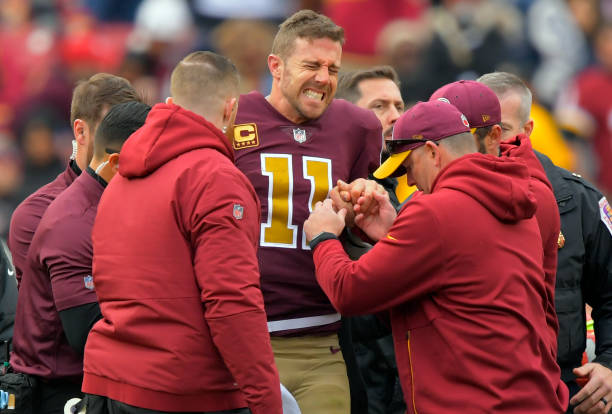 Washington Redskins quarterback Alex Smith grimaces after being helped up after suffering an lower leg injury during a game between the Washington...
