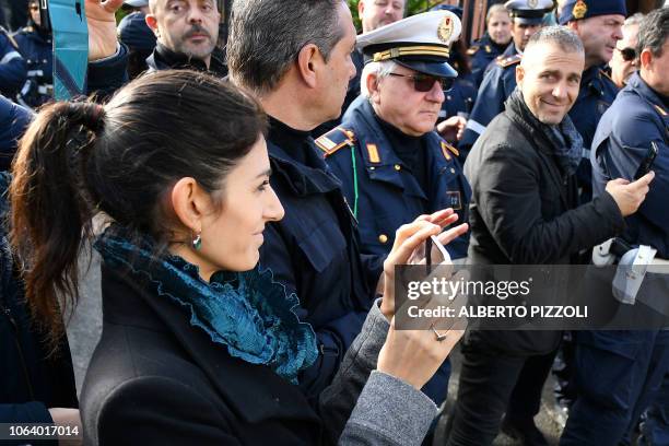 Rome mayor Virginia Raggi takes a video with her mobile phone as bulldozers demolish one of eight illegally built villas seized by Rome police to the...