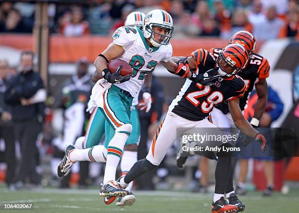 Brian Hartline of the Miami Dolphins runs with the ball while defended by Leon Hall of the Cincinnati Bengals during the NFL game at Paul Brown...