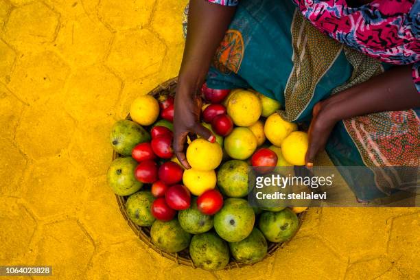frau hält korb mit tropischen früchten in afrika - ruanda stock-fotos und bilder