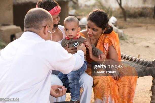 medico pediatra che esamina ragazzo malato in villaggio - india foto e immagini stock