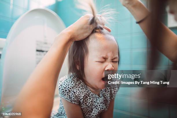 lovely yawning toddler girl sitting on the toilet while her mom tiding her hair, - childrens closet stockfoto's en -beelden