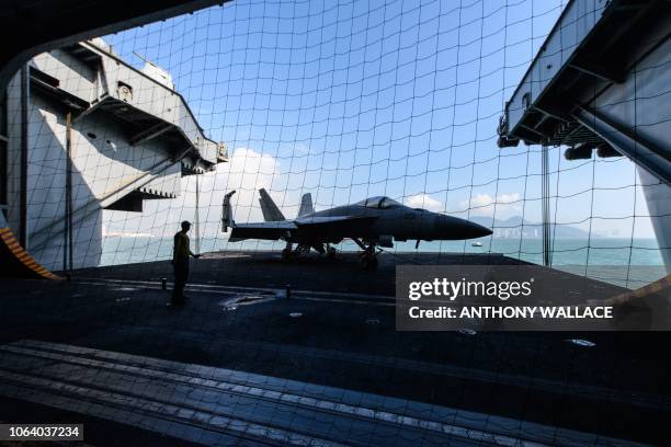 Sailor on board the US Navy's USS Ronald Reagan aircraft carrier stands on a lift transporting a single-seat F/A-18E Super Hornet to the lower deck...