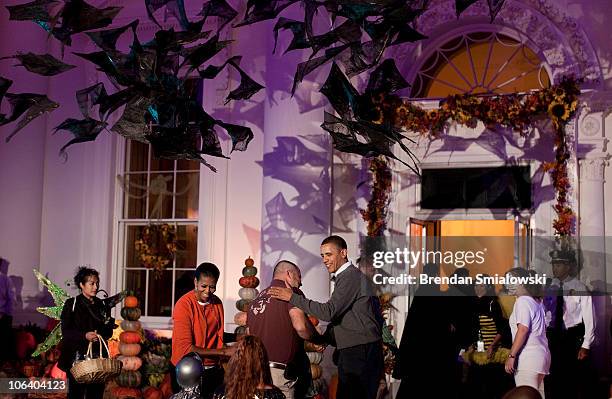 First lady Michelle Obama and U.S. President Barack Obama greet trick or treaters and their parents at the White House October 31, 2010 in...