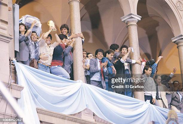 Diego Maradona of Argentina holds the World Cup trophy to celebrate with teammates at Casa Rosada on June 30, 1986 in Buenos Aires, Argentina.