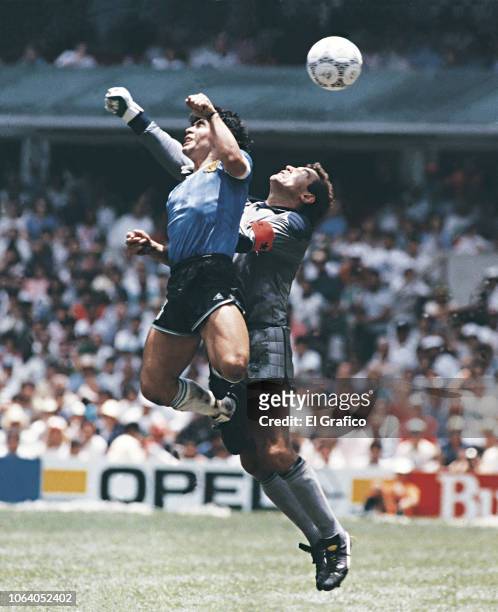 Diego Maradona of Argentina uses his hand to score the first goal of his team during a 1986 FIFA World Cup Quarter Final match between Argentina and...