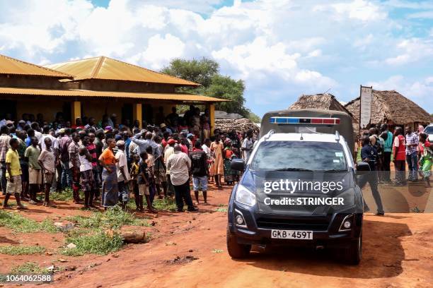 Villagers gather beside a police vehicle as they look at an area where a grenade exploded during an attack by a gang in Chakama village of the...