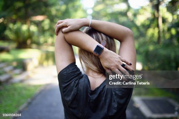 woman stretching on a trail with a fitness tracker - fitnesstracker stock pictures, royalty-free photos & images