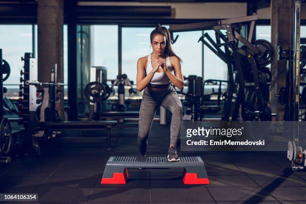 young woman exercising on step aerobics equipment at gym - stepping stock pictures, royalty-free photos & images