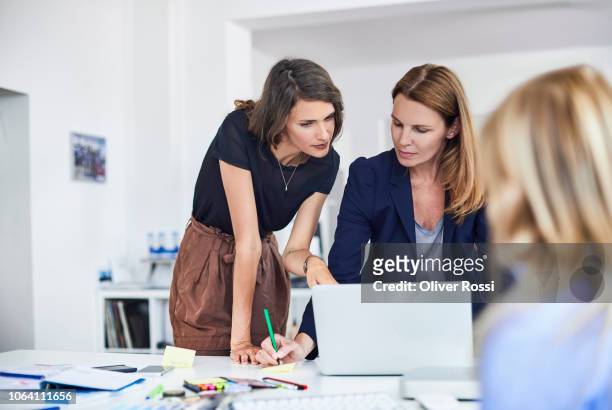 three businesswomen working at desk in office - organised group stock-fotos und bilder