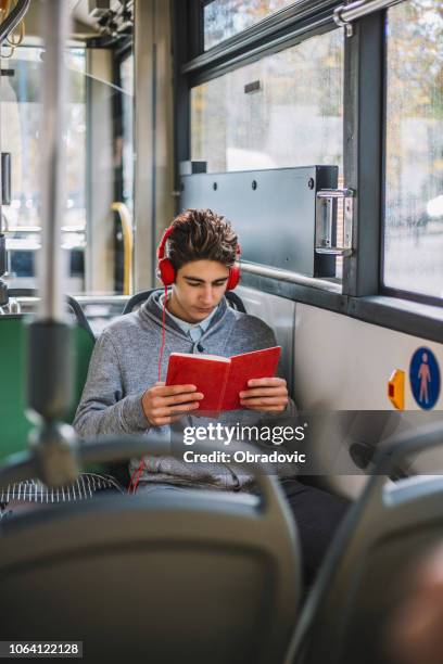 student reading a book and listening music in the bus - city book stock pictures, royalty-free photos & images