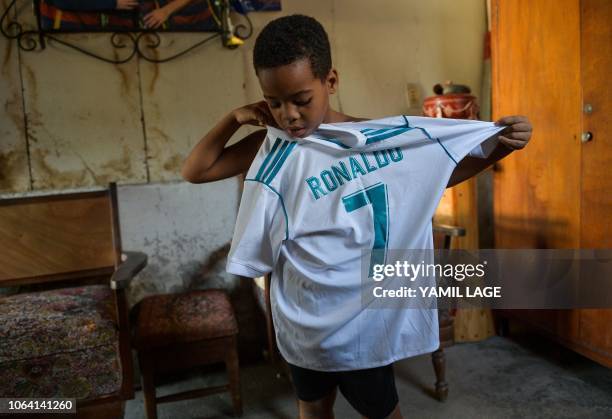 Cuban child shows a T-shirt of his favorite football player, Portuguese Ronaldo of when he played for Spain's Real Madrid, at his house in Havana, on...