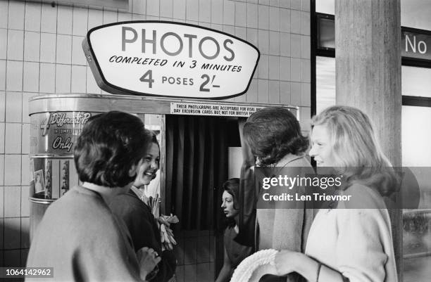 View of a group of young women waiting to use a Photo Booth machine to obtain passport style photos at Gatwick Airport in East Sussex, England on...