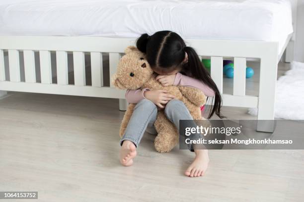 sad little girl sitting on - kind teddy sitzt stock-fotos und bilder