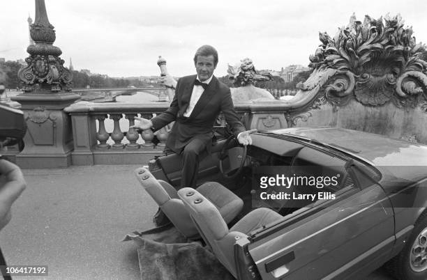 British actor Roger Moore on set of the James Bond movie 'A View to a Kill' with half a car during filming in Paris, France in August 1984.