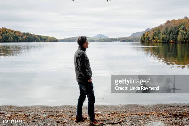 a man contemplating a calm lake - blickwinkel vom autorücksitz stock-fotos und bilder