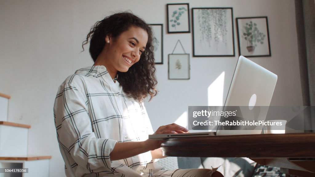 Charmante junge Frau, die Eingabe auf Laptop-Computer zu Hause.