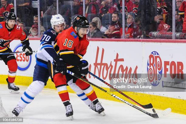Derek Ryan of the Calgary Flames battles for the puck against Joe Morrow of the Winnipeg Jets during an NHL game at Scotiabank Saddledome on November...