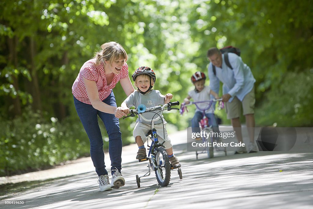 Family outside, children learning to ride bikes