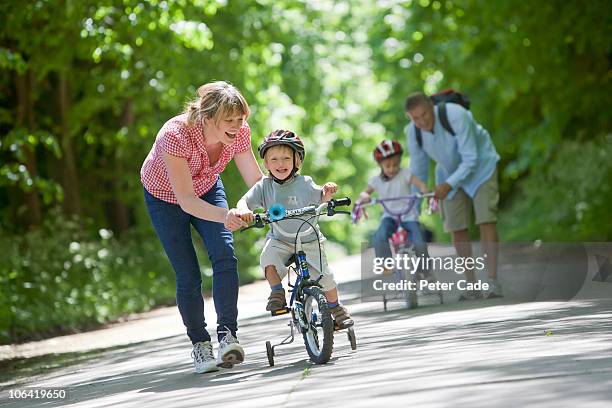 family outside, children learning to ride bikes - 2 year old blonde girl father stock pictures, royalty-free photos & images