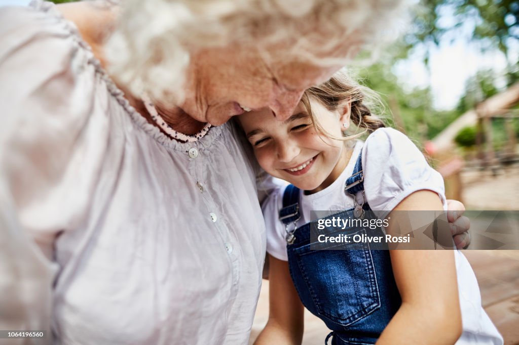 Happy grandmother embracing granddaughter outdoors