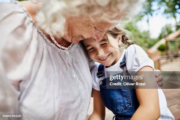 happy grandmother embracing granddaughter outdoors - granddaughter stockfoto's en -beelden