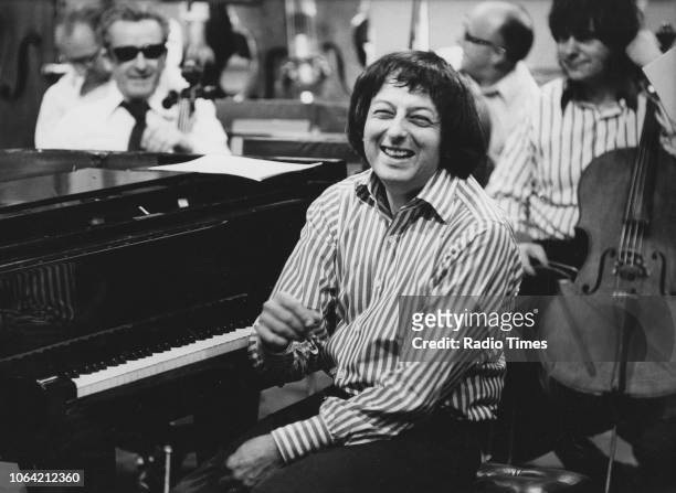 Portrait of conductor Andre Previn laughing as he sits at the piano, May 15th 1974.
