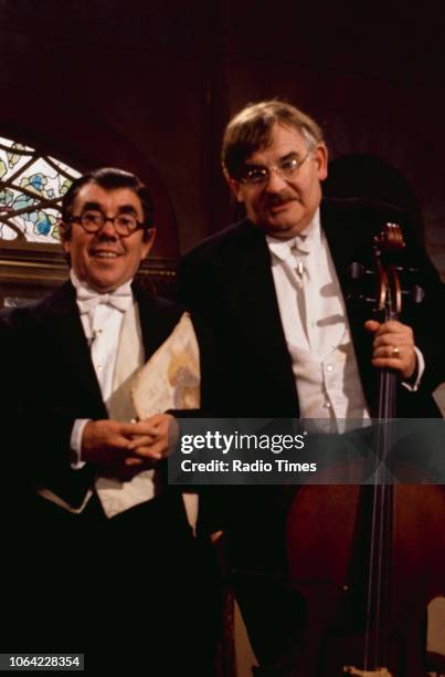 Comedians Ronnie Corbett and Ronnie Barker playing musical instruments in a sketch from the television series 'The Two Ronnies', 1978.