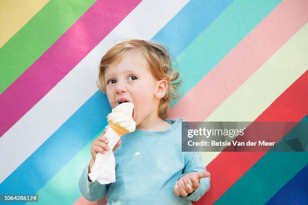 toddler eats icecream against colorful wall. - innocent stock pictures, royalty-free photos & images