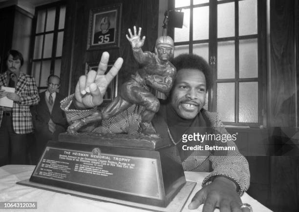 Archie Griffin of Ohio State holds up two fingers as he poses with the Heisman Trophy after he was named winner of the coveted bronze trophy for the...