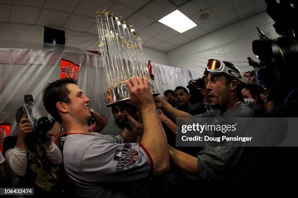 Buster Posey and Andres Torres of the San Francisco Giants celebrates with the trophy in the locker room after the Giants won 3-1 against the Texas...