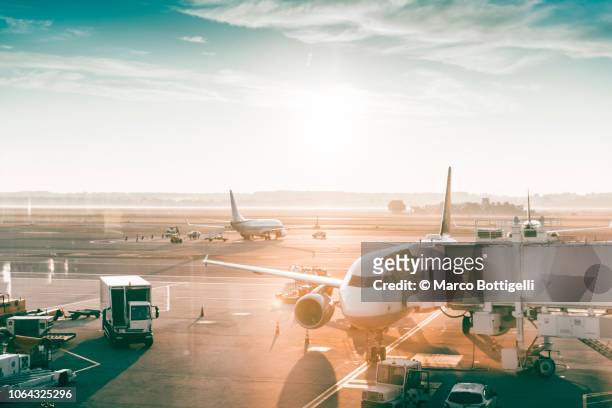airplanes in an airport at sunrise - flughafen stock-fotos und bilder