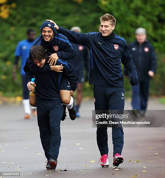 Carlos Alberto Vela jumps on the back of team mate Tomas Rosicky as Nicklas Bendtner laughs during a training session ahead of the UEFA Champions...